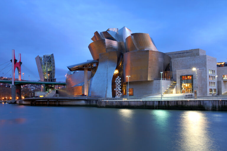 Guggenheim Museum Bilbao illuminated beside the Nervión River at dusk
