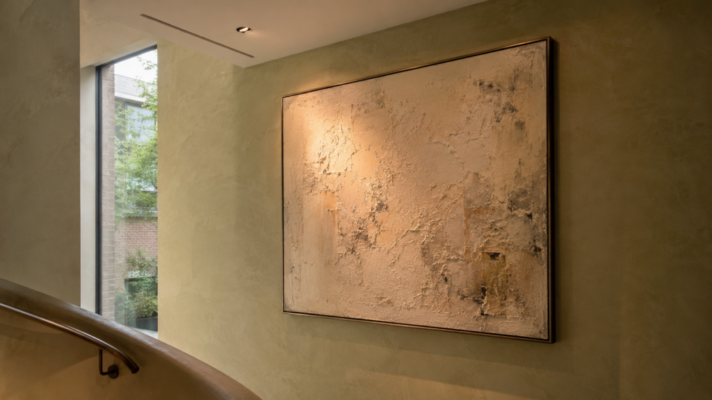 Adjustable recessed downlight directing a controlled beam onto a large textured artwork beside a stairway.