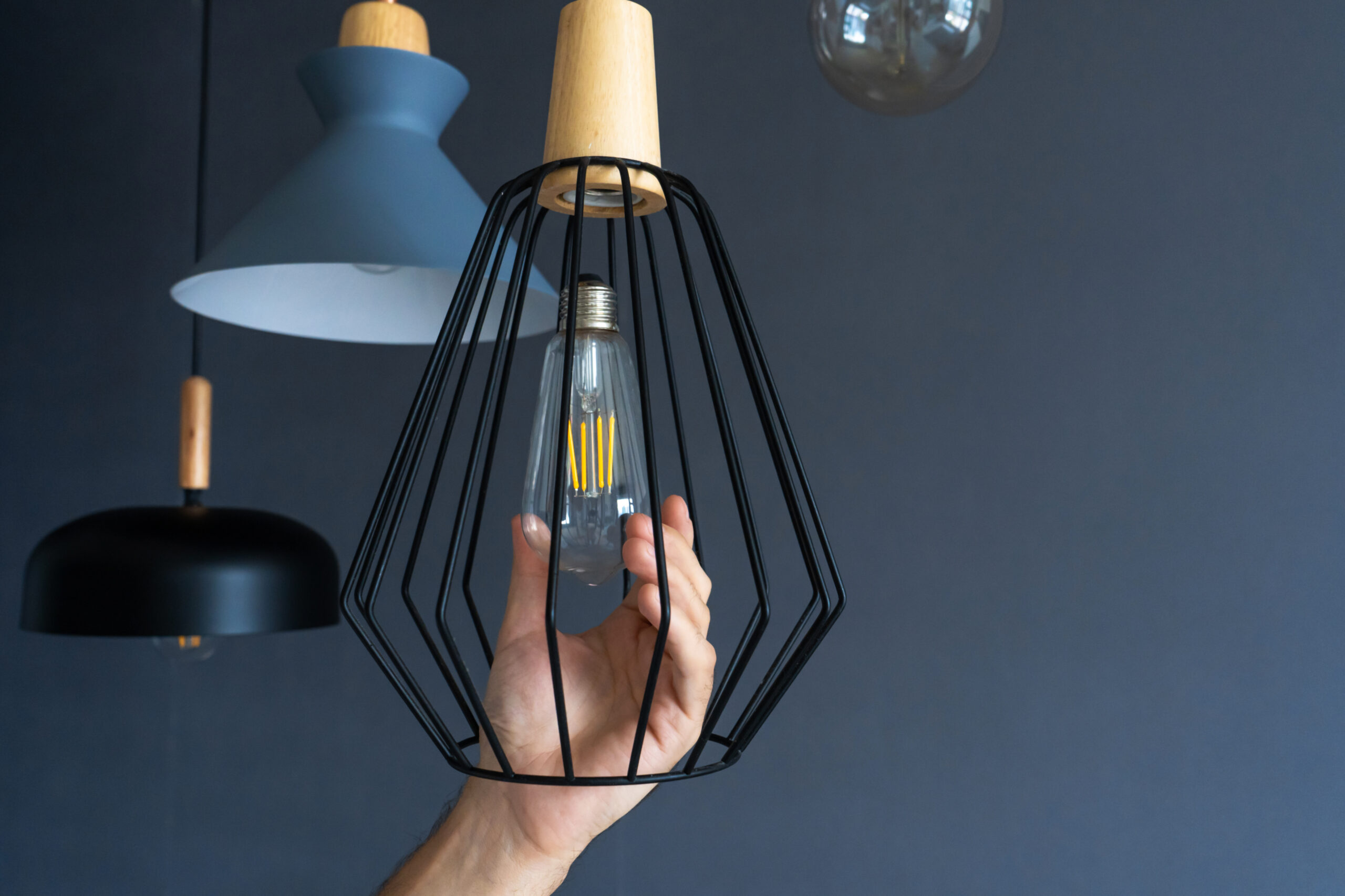 Person checking an LED bulb in a pendant light fitting before installation